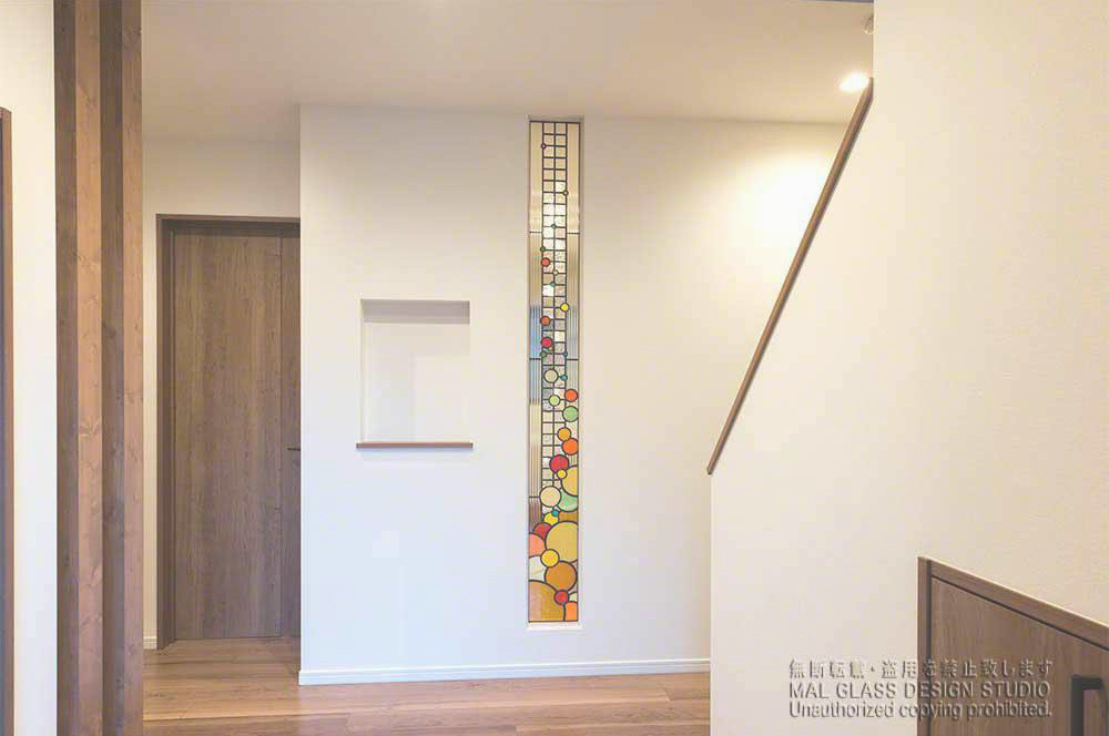 現代的なステンドグラス。縦に長いステンドグラスを玄関から見た写真。