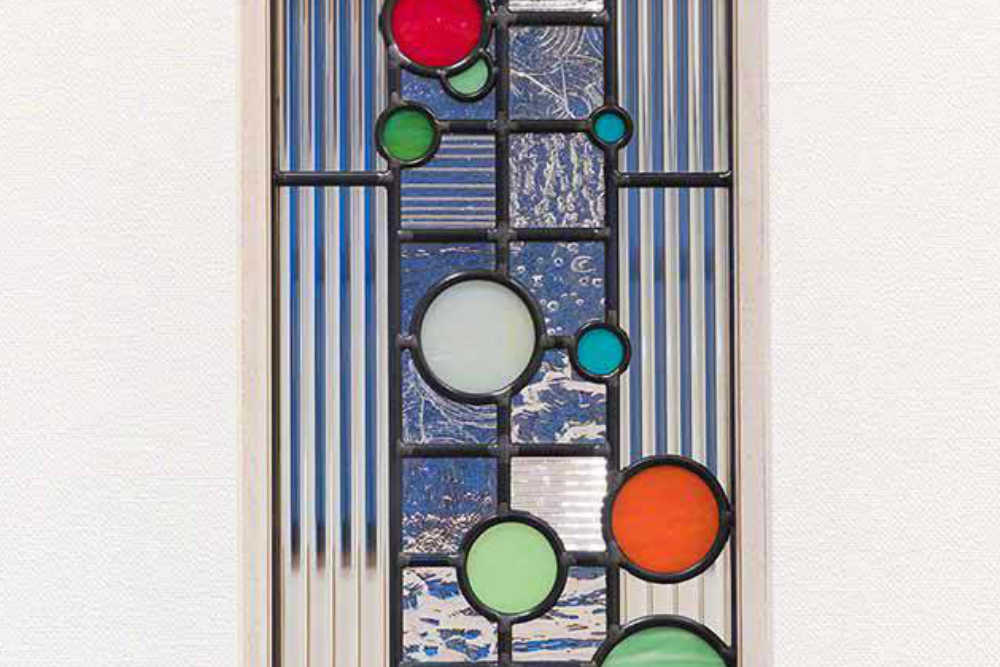 カラフルな色のガラスがリズミカルに跳ねるステンドグラスのクローズアップ写真。