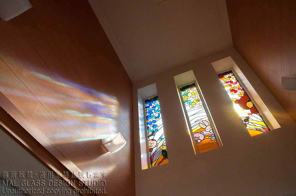 かわいいステンドグラスの施工例。3枚一組のステンドグラスと壁面に映る影。