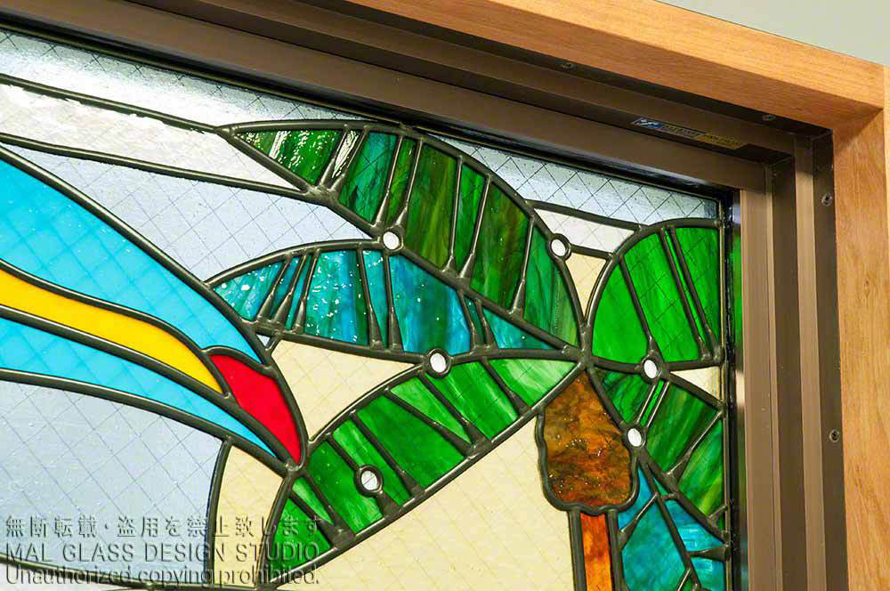具象的なステンドグラスの施工例。オオハシのくちばしとヤシの木のステンドグラス。