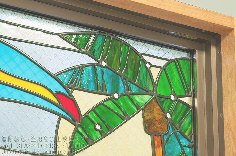 具象的なステンドグラスの施工例。オオハシのくちばしとヤシの木のステンドグラス。