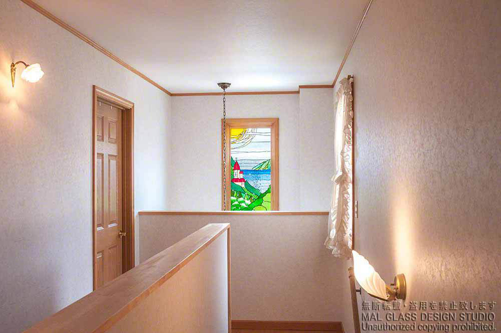 山の中腹に赤い屋根のお城が見えるステンドグラスの風景画。