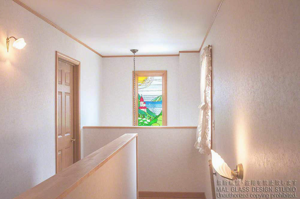 山の中腹に赤い屋根のお城が見えるステンドグラスの風景画。