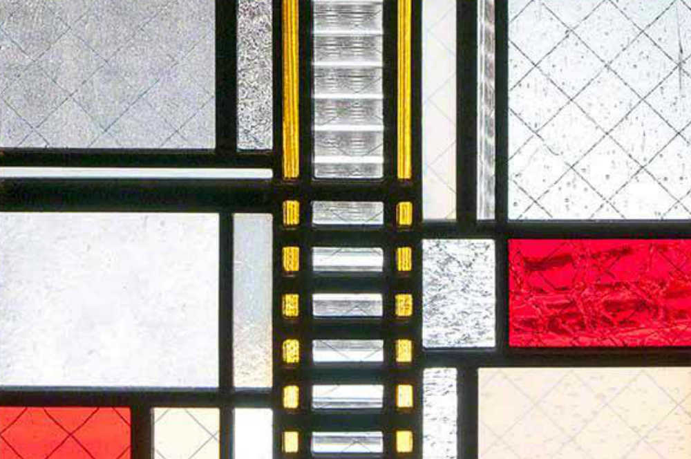 シンプルな3枚一組のステンドグラス。赤い色ガラスを使った中央パネルの下の部分のクローズアップ。